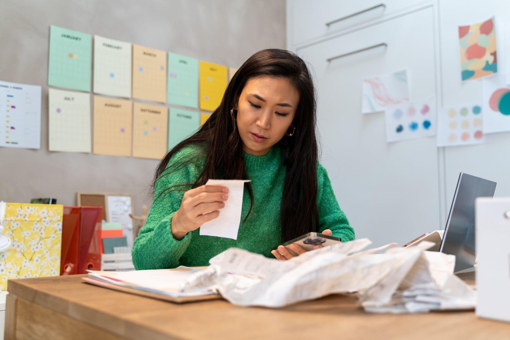 Vrouwelijke ondernemer bekijkt alle papieren en rekeningen.