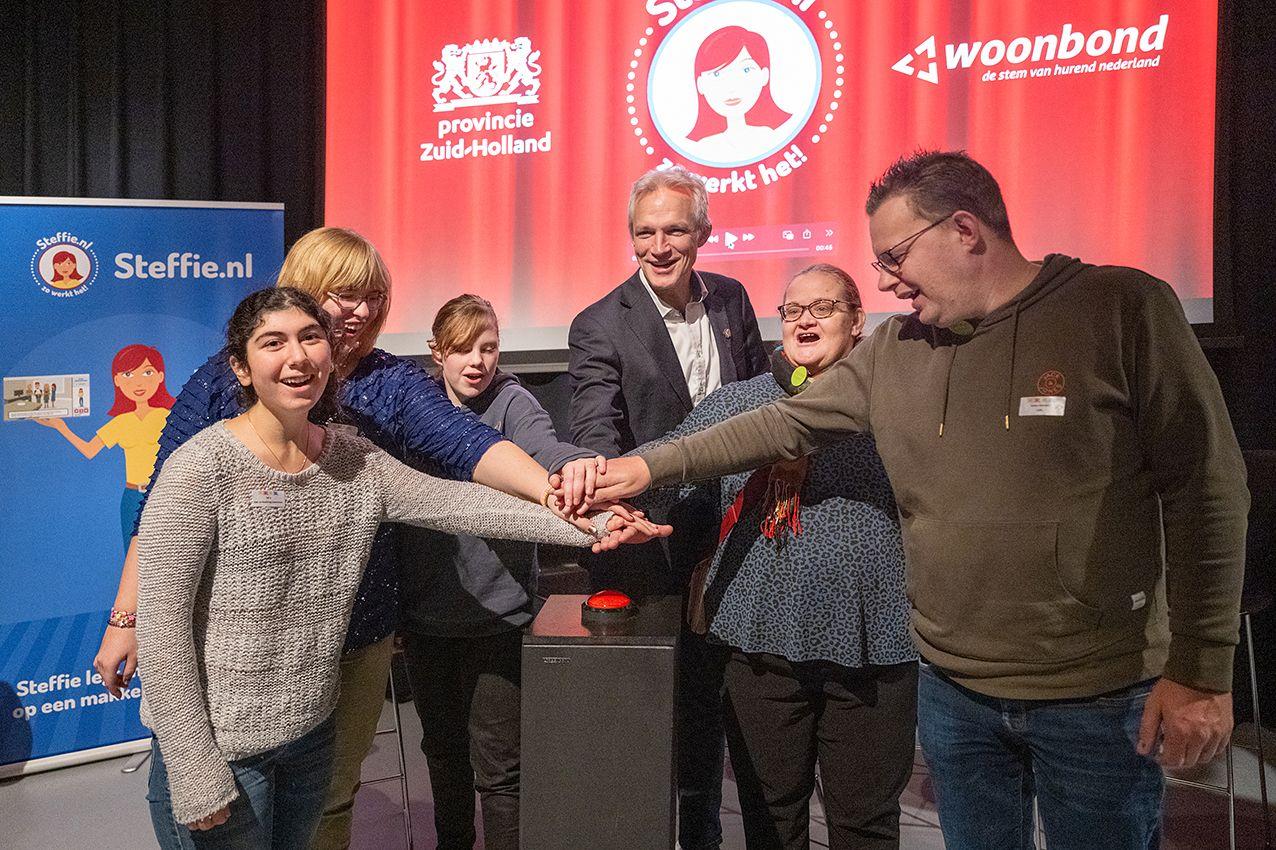 Verschillende mensen drukken op een grote, rode knop om de website Steffie.nl te lanceren.
