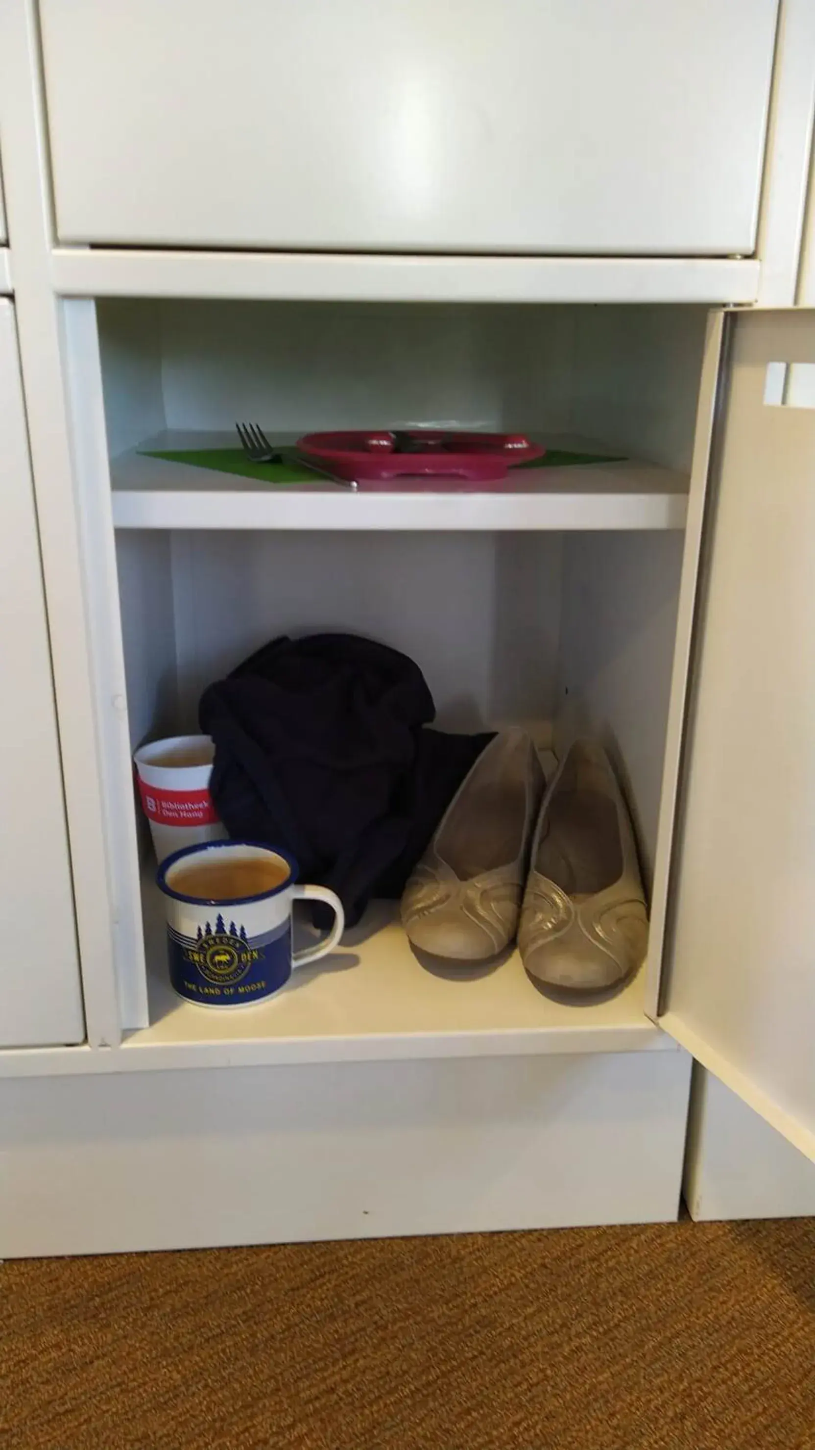 Foto van de binnenkant van een locker. Je ziet theemokken, schoenen en een extra vest.