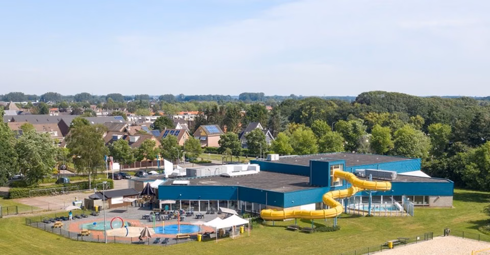 Luchtfoto van een zwembad met gele glijbaan.